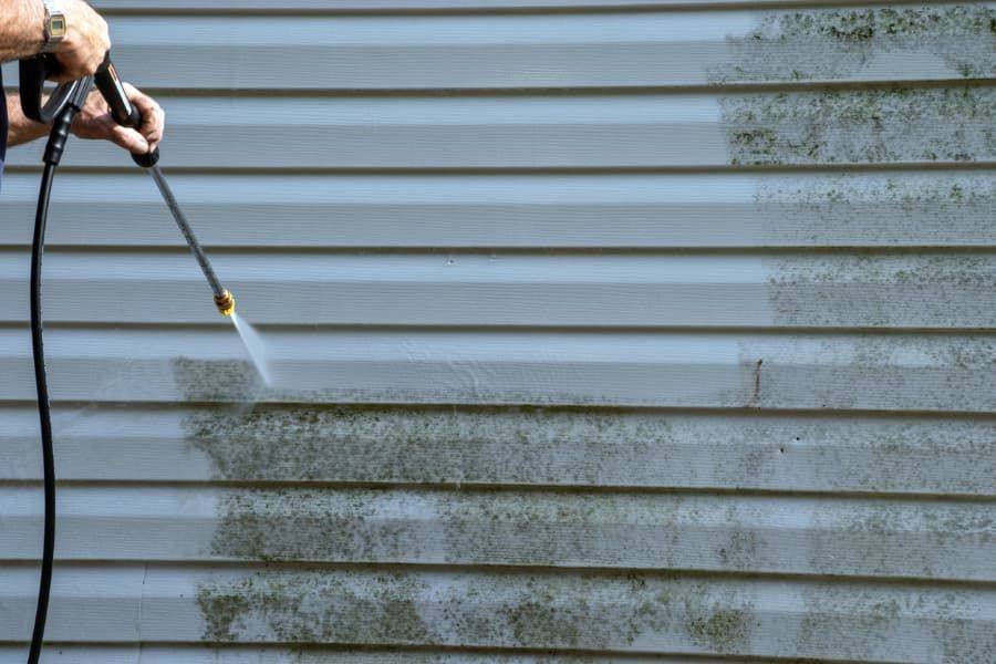Vinyl siding half cleaned, showing mildew removed by soft washing